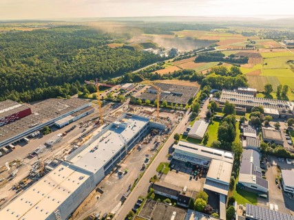 A bird's eye view of an industrial area with construction cranes and factory buildings, surrounded