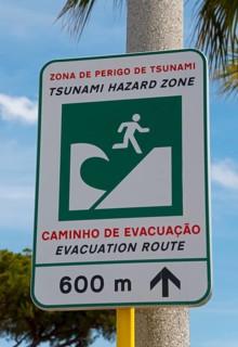 Warning sign for a tsunami danger zone near the beach with evacuation notice, Vilamoura, Faro,