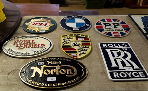 Replica reproduction metal signs related to motoring brands on display at auction, UK