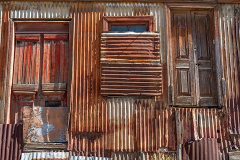 Boarded up and neglected house with a façade of rusty corrugated iron, city of Punta Arenas,