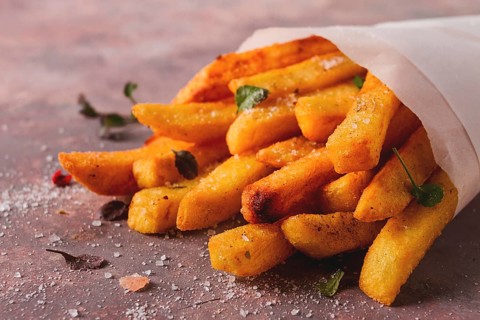 Fried French fries, in a paper bag, on an abstract background, no people, rustic