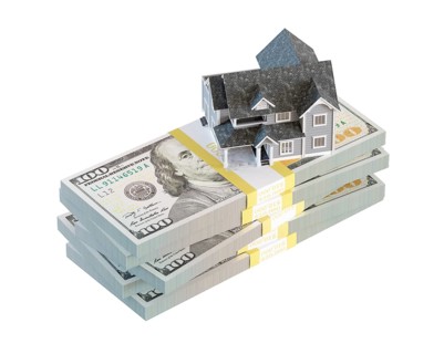 Miniature house resting on stack of thousands of dollars cash isolated on a white background