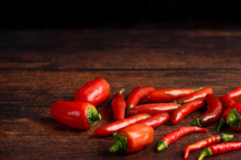 Red peppers scattered on a dark wooden surface, food photography