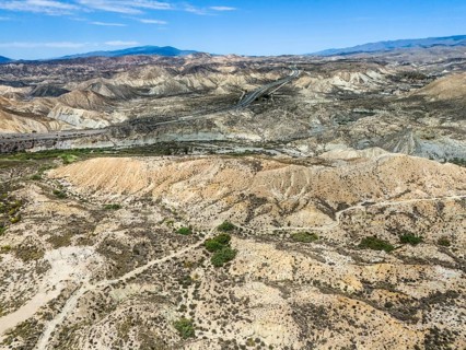 Dry desert landscape with rugged hills and a road under a clear sky, Aerial view, Tabernas Desert,