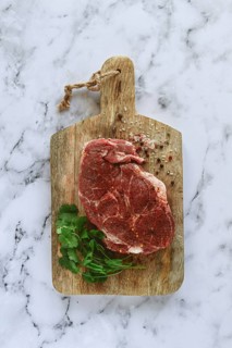 Raw pork steak, pork neck, on a chopping board, marble table, top view, with spices and coriander,