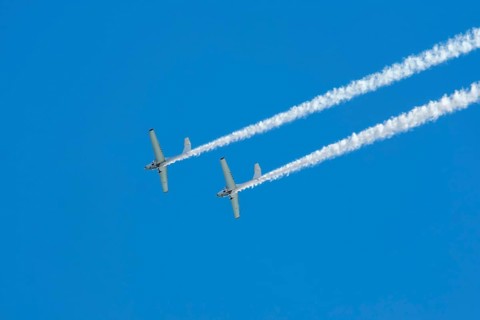 Stunt aerobatic plane performing stunts in blue sky with smoke trail. Concept of teamwork,