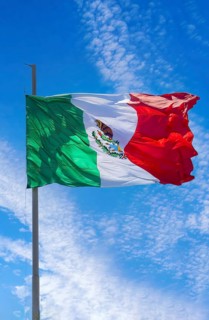 Los Cabos, Mexico, Mexican tricolor national striped flag proudly waving at mast in the air with