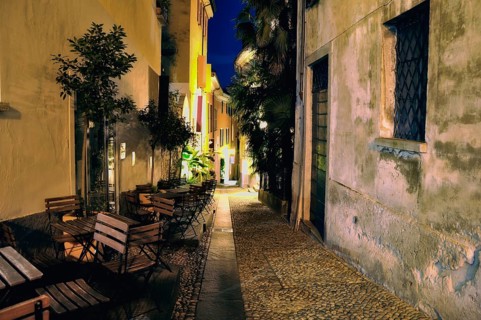 Old Narrow Alley Illuminated at Night with Chairs and Tables in City of Locarno, Ticino,