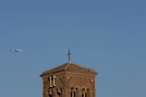 Boeing 737 jet passenger aircraft of Ryanair flying in a blue sky over an ancient city building,