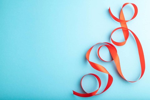 Red coral ribbon on a blue pastel background. Celebration concept. Top view, copy space, flat lay