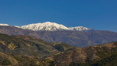 Snow-capped mountains with green valleys under a clear blue sky, Lefka Ori, White Mountains,