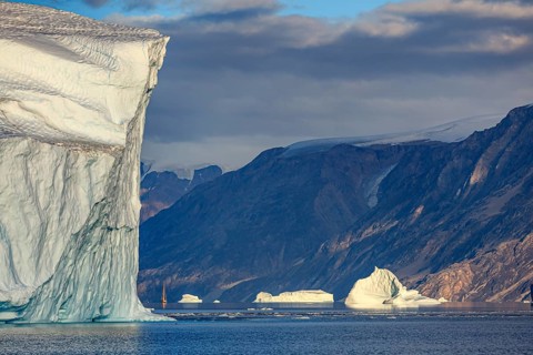 Sailing boat, ship in fjord in front of large icebergs and mountains, evening light, Scoresby