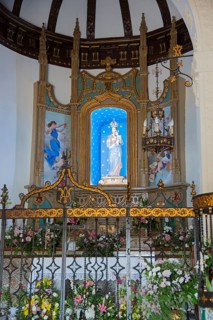 Artfully decorated church altar with flowers, statue of the Virgin Mary and golden ornaments,
