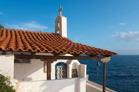 Chapel building with red bricks by the sea under a blue sky, radiates peace, Church of Agios