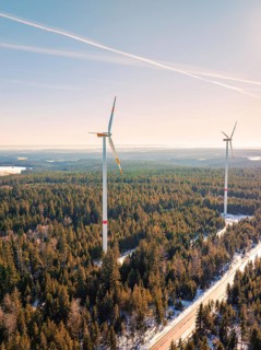 Two wind turbines protrude from a snow-covered forest, Seewald, Black Forest, Germany, Europe