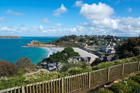 Panorama of a coastal town with houses on the beach, blue sky and trees, view of sandy beach