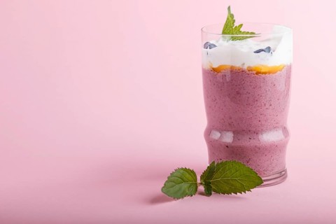 Smoothie with honeysuckle, linen and chia in a glass on pink pastel background. side view, close