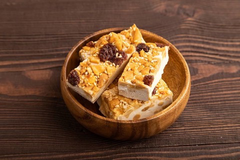 Traditional candy nougat with nuts and sesame on brown wooden background. side view, close up