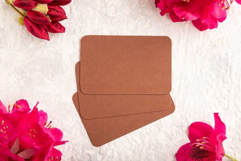 Brown business card with purple azalea flowers on gray concrete background. top view, flat lay,
