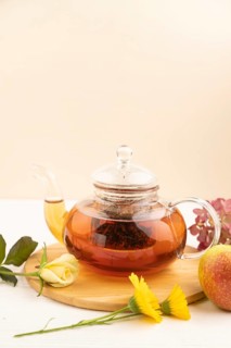 Red tea with herbs in glass teapot on white wooden background. Healthy drink concept. Top view,