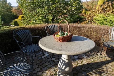 Garden furniture, stone table with a basket with decorative pumpkins. Modern landscape design with