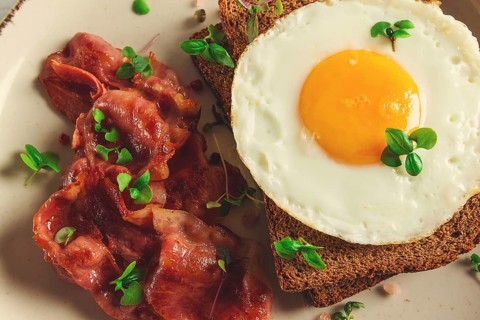 Breakfast, fried egg with bacon, micro-green, on a light background, no people, selective focus
