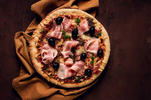 Pizza with prosciutto and mushrooms, bacon, olives, homemade, top view, no people