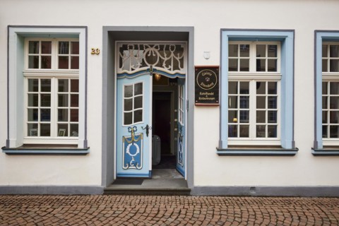Magnificent entrance with blue, decorated entrance door to the art trade and restorations of the