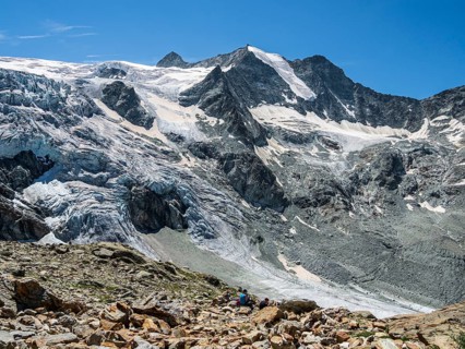 Tourists at mountain hut Cabane de Moiry, viewing at the retreating Moiry glacier, Valais,