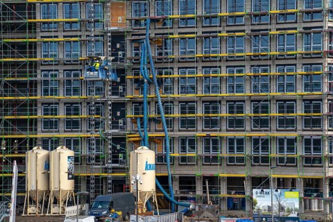 Large construction site, scaffolded shell of an office building complex, air hoses for construction