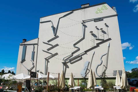 Façade of a building with large, attached instruments as an art installation, mural, Green Symphony