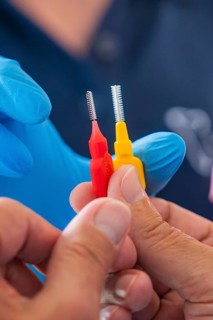 Two interdental brushes in red and yellow are held by hands, dental practice, Germany, Europe