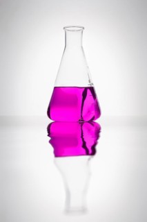 A glass bottle with purple liquid in a laboratory