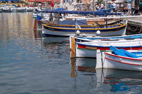 Small colourful boats in the harbour, reflected in the calm water, harbour of Cassis, Provence,
