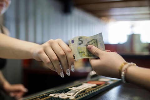 Symbol photo on the subject of cash payment in the catering trade. A woman pays with 5 euros cash