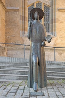 Sculpture Pilgrim with staff and scallop shell and monument to the Way of St James in front of St