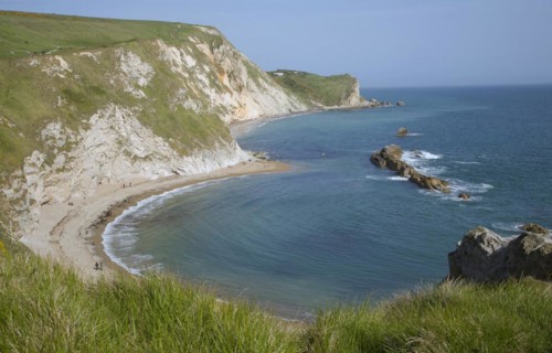 A line of limestone stumps cross Man o' War bay on the Jurassic coast near Lulworth Cove, Dorset,