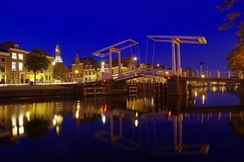 An illuminated canal with bridge and historic buildings in the background at night, evening mood,