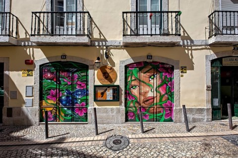 Colorful graffiti art on store shutters enriching the urban street atmosphere, Alfama, Lisbon