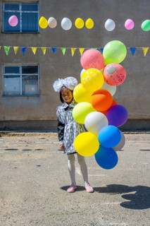 Happy schoolgirl with colourful balloons on the first day of school, Issyk-Kul region, Kyrgyzstan,