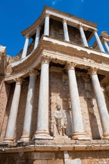 Close-up of a statue in front of ancient columns and stone walls, an example of Roman architecture