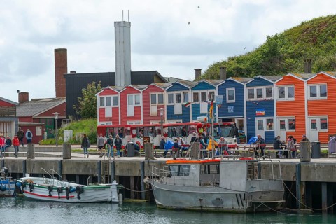 Colourful lobster shacks in the lowlands, promenade, shops, harbour with boats, many people,