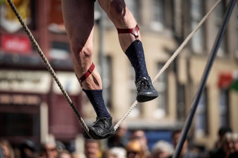 Feet balancing on a tightrope, street artists performing high-wire acrobatics, world's largest