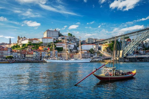 View of Porto city and Douro river with traditional boats with port wine barrels and sailing ship