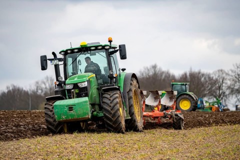 Tractor with a plough preparing the soil of a field for planting, Agriculture, Spring