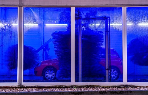 Car in an automatic car wash, car wash tunnel, cleaning foam is sprayed on, rotating brushes clean