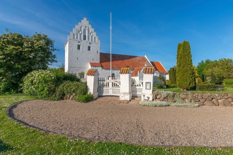 Whitewashed church in Dalby, side view, red roof, cemetery, stepped gable, entrance gate, stone