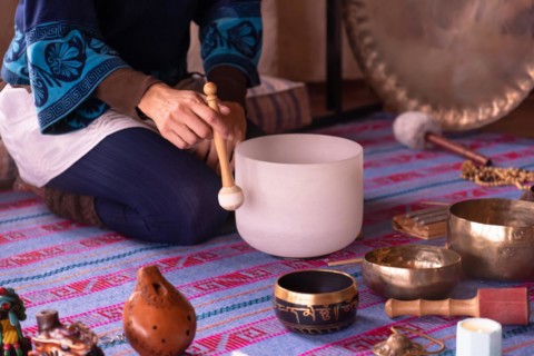 Close-up of a woman's hands playing a quartz singing bowl, while guiding a sound meditation