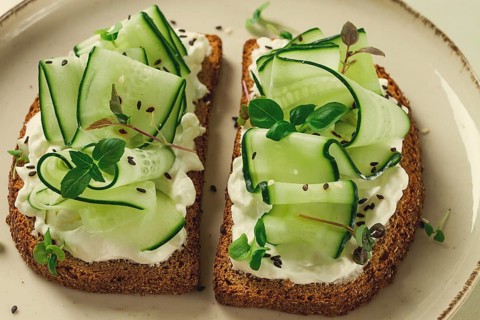 Breakfast, cereal bread sandwiches, cream cheese, sliced cucumber, with micro greenery on a light