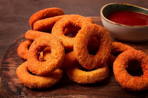 Crispy chicken rings, fried, on a wooden board, close-up